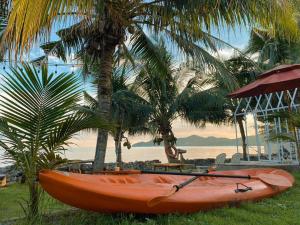 柴老海滩Windy Seaview Resort的棕榈树旁的草地上坐着一个橙色皮艇
