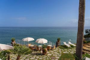伊斯基亚欧陆马尔酒店的一个带椅子和遮阳伞的庭院和大海