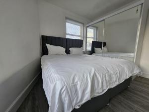 伦敦Battersea Park apartments的卧室配有一张大白床和大镜子