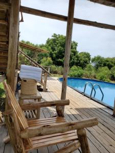 WansekoNKUNDWA NILE VIEW LODGE的一个带椅子的木甲板和一个游泳池