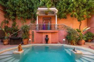 马拉喀什印度宫殿酒店的带阳台的大楼前的游泳池