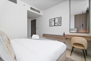 迪拜Nasma Luxury Stays - Elegant 1BR With Stunning View of Park Avenue的白色卧室配有床和椅子