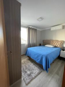 托雷斯Apto duplex Lagoa do Violão的一间卧室配有一张带蓝色毯子的床和窗户。