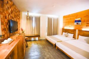 归仁Rustic Hotel Quy Nhon Powered by ASTON的酒店客房设有两张床和电视。