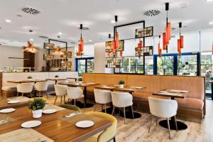 塞维利亚塞维利亚希尔顿花园酒店的餐厅设有木桌、椅子和窗户。