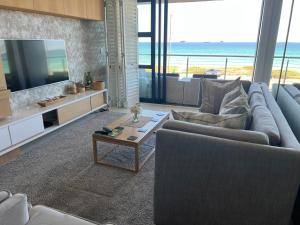 布鲁堡史特兰Blouberg Luxury Beachfront Apartment的带沙发、电视和桌子的客厅