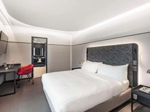 圣地亚哥Pullman Santiago Vitacura的酒店客房带白色的床和红色椅子