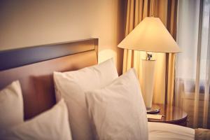 威斯巴登纳索尔霍夫酒店的一张带白色枕头的床和一张带台灯的桌子
