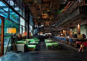 雅加达The Orient Jakarta, a Royal Hideaway Hotel的餐厅设有绿色的沙发、桌子和窗户。