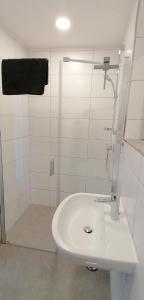 Pension Lahntal的白色的浴室设有水槽和淋浴。