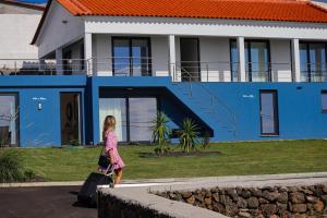英雄港Villas da Salga的在一个蓝色房子前面行走的年轻女孩
