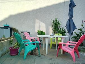 圣但尼une maison en ville的一张桌子,上面摆放着五颜六色的椅子和一把雨伞