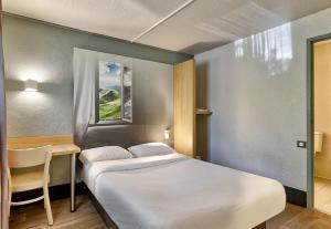 克莱蒙费朗B&B HOTEL Clermont-Ferrand Le Brézet Aéroport的卧室配有1张床、1张桌子和1把椅子
