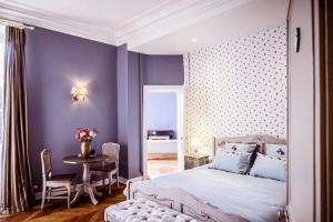 Vallon-sur-GéeChâteau de la Grange Moreau的卧室设有紫色墙壁、一张床和一张桌子