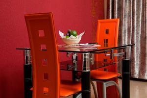 MeruGatimene Gardens Hotel的一张桌子、橙色椅子和一碗水果
