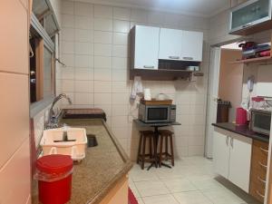 瓜鲁雅Apartamento Astúrias a menos de 50m da praia的一间带水槽和微波炉的小厨房