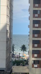 瓜鲁雅Apartamento Astúrias a menos de 50m da praia的从两栋建筑中可以欣赏到海滩美景