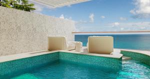 卡斯特里Sandals Regency La Toc All Inclusive Golf Resort and Spa - Couples Only的一个带两把椅子的游泳池以及大海
