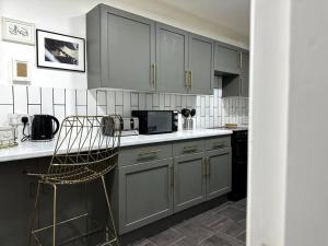 伦敦Luxury 3 Bed Home In London的厨房配有灰色橱柜和椅子