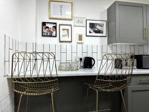 伦敦Luxury 3 Bed Home In London的厨房配有带2把金属椅的台面