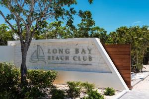 Long Bay HillsLong Bay Beach Club的砖墙上的一个长长的海湾高杆标志