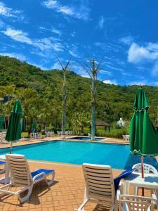 弗洛里亚诺波利斯Canto da Ilha的度假村内带椅子和遮阳伞的游泳池