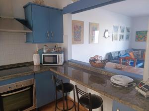法马拉Casa de Famara的厨房配有蓝色橱柜和带凳子的台面