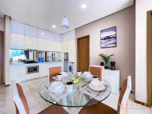 吉隆坡Soho Suites KLCC by Wakely Kuala Lumpur的厨房以及带玻璃桌和椅子的用餐室