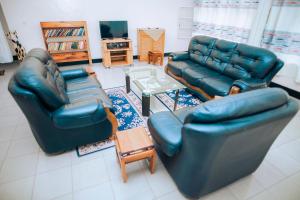 MuhariPeace Guest House的客厅配有两张真皮沙发和一张桌子
