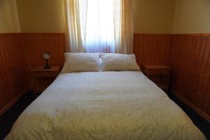 圣佩德罗·德·阿塔卡马Hostal Puritama的卧室内的一张床位,设有两张桌子和一扇窗户