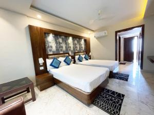 普里Hotel AMBIKA PALACE PURI的一间卧室配有两张带蓝色枕头的床