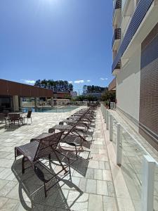 卡达斯诺瓦斯Caldas Novas - 2024 - diRoma Spazzio acesso ao Vulcão - com Piscina do hotel 24 horas的坐在建筑物旁边的一排长椅