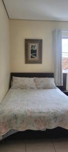贝洛奥里藏特Kitinet Central的一间卧室配有一张带花卉床罩的大床
