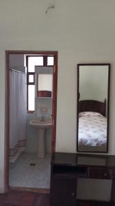 科帕卡巴纳Hostal La Chacarilla的浴室设有镜子、一张床和一个水槽
