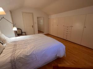 VésenazLe Cottage的卧室配有一张白色的大床,铺有木地板