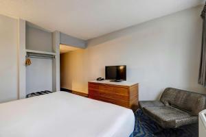 阿林顿Motel 6 Arlington TX Entertainment District的一间卧室配有一张床、一台电视和一把椅子