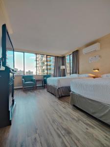 温哥华Divya Sutra Suites on Robson Downtown Vancouver的酒店客房设有两张床和一台平面电视。