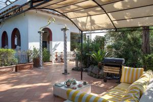 伊斯基亚Villa Gianturco - Luxury In The Green Island的一个带顶棚、沙发和烧烤架的庭院