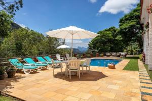 彼得罗波利斯Casa em Araras: Piscina, sauna e serviço incluído!的游泳池旁的天井配有椅子和遮阳伞。