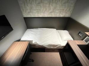 西之表市种子岛阿拉基酒店的小房间设有一张小床和两张书桌