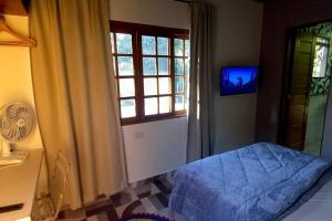 圣罗克Casinha acolhedora da mata - Rota do Vinho的一间卧室设有一张床、一个窗口和一台电视