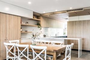 拜伦湾A Perfect Stay - 11 James Cook Apartments的厨房配有木桌和白色椅子