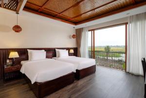 宁平Athena Premier Resort Ninh Bình的带阳台的客房内的两张床