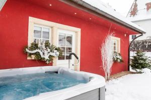 瑟温Doller Villa 4 stars Hot Tub Mountain Ski Ballon d'Alsace的雪中红色房子前面的热水浴池
