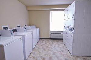 普莱森顿Savannah Suites Pleasanton的洗衣房配有白色家电和窗户