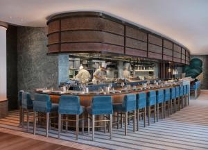 伦敦伦敦帕克巷四季酒店的餐厅设有长长的酒吧,配有蓝色椅子