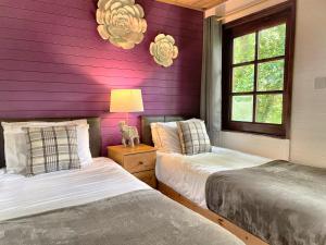 卡马森Woodland Lodge’s St Clears的紫色墙壁客房的两张床