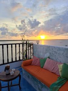 拉穆Pwani House - Lamu Seafront的阳台的沙发,享有日落美景