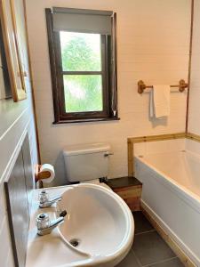 卡马森Woodland Lodge’s St Clears的一间带水槽和卫生间的浴室以及窗户。