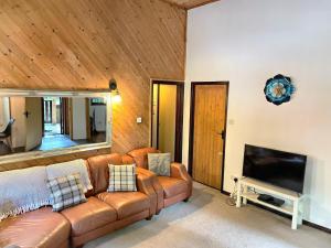 卡马森Woodland Lodge’s St Clears的客厅配有真皮沙发和电视